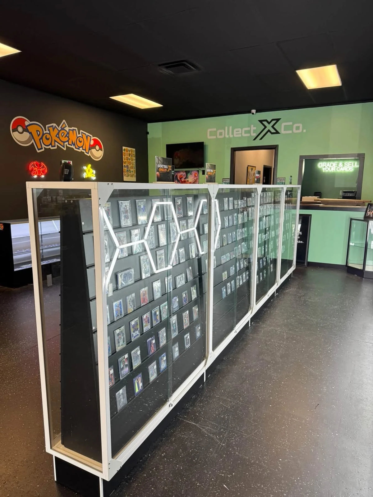 Illuminated trading-card display cases beneath the Pokémon and CollectX Co. wall signs