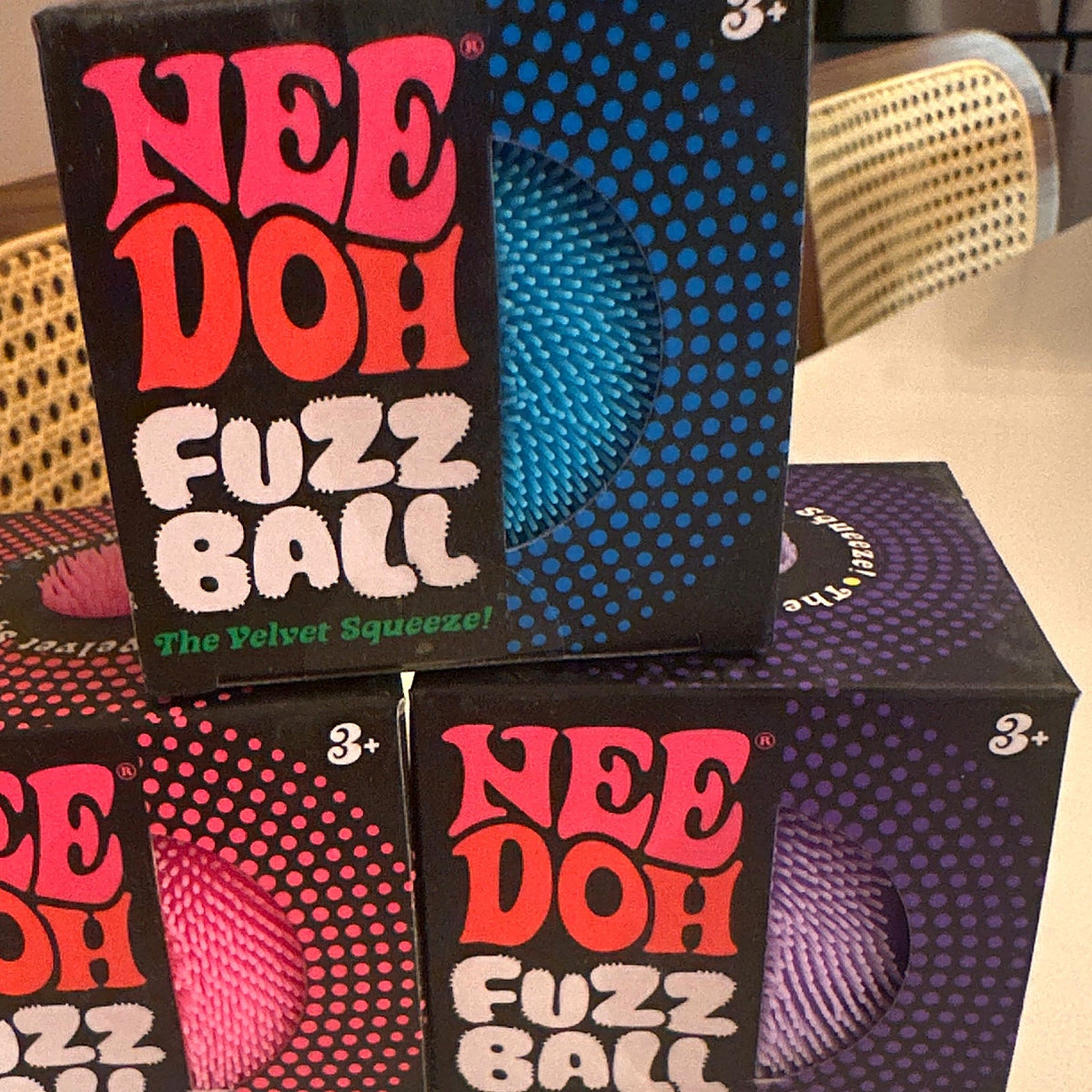 NeeDoh Fuzz Ball velvet squeeze toy boxes in blue, pink and purple